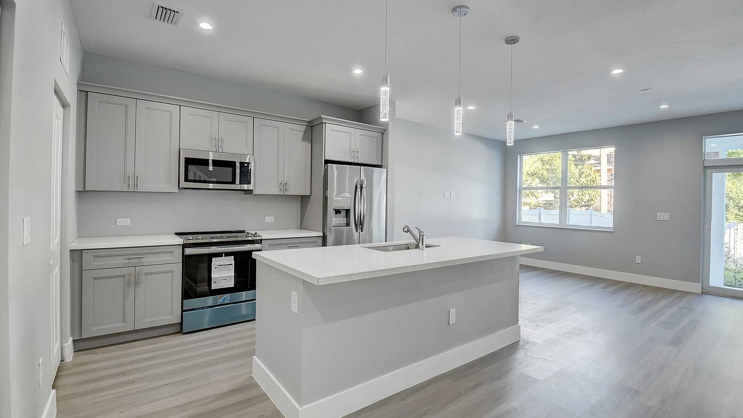 Modern open-concept kitchen with elegant pendant lighting, sleek stainless steel appliances, and a spacious island with seating.