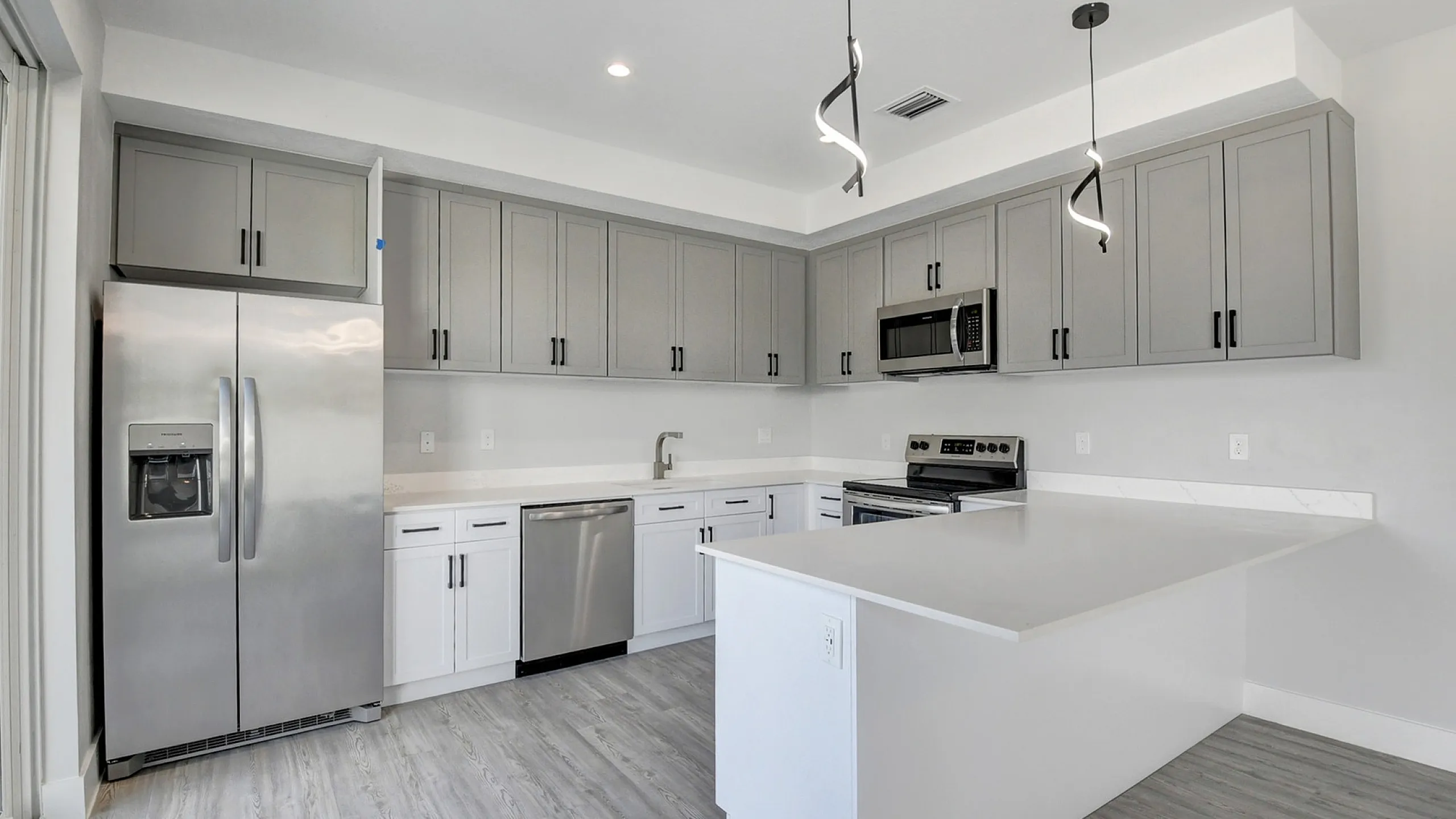 Sleek modern kitchen with spacious white countertops, stainless steel appliances, and stylish pendant lighting.