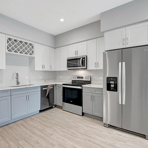 Modern kitchen with sleek stainless steel appliances, elegant dual-tone cabinets, and a built-in wine rack creating a chic and functional cooking space.