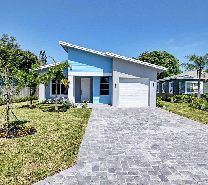 Charming modern blue and white house with sleek architecture, spacious driveway, and lush green landscaping.