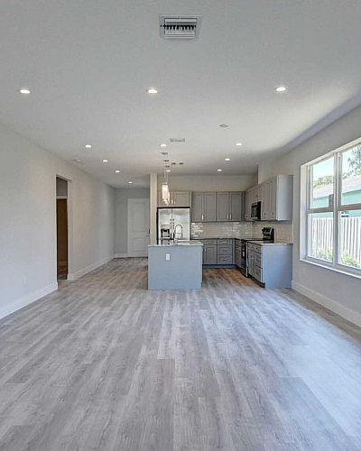 Bright and modern open-plan living space featuring sleek hardwood floors and stylish kitchen with ample natural light through large windows.