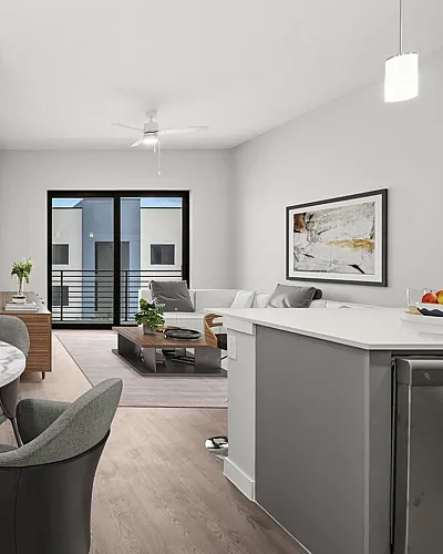 Modern open-concept living space with elegant dining area, stylish kitchen, and cozy living room leading to a balcony.