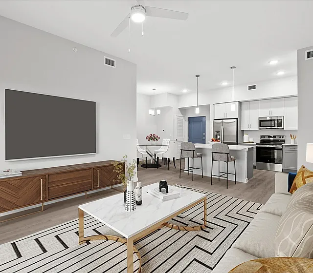 Modern open-concept living area with cozy seating, stylish decor, and a sleek kitchen island under bright pendant lighting.