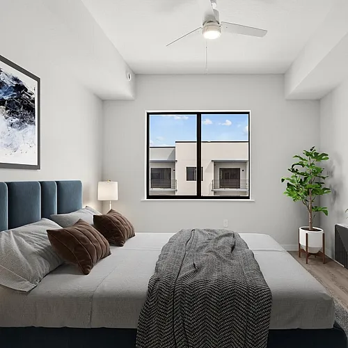 Elegant bedroom with plush navy bed, modern decor, and large window offering natural light and a lovely view.