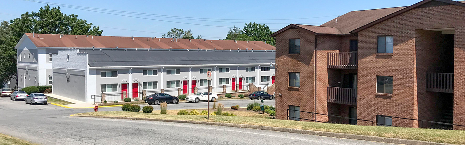 Inviting apartment complex with modern design, featuring red doors and lush landscaping, offering a welcoming residential environment.