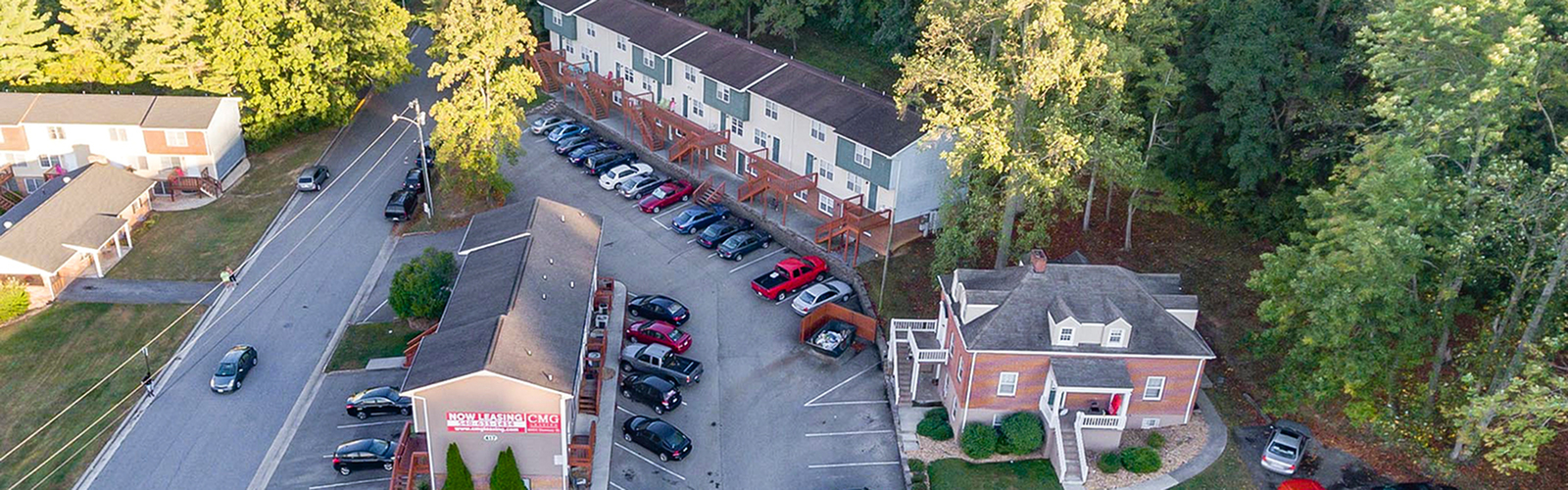 Charming apartment complex nestled in lush greenery with ample parking and a warm neighborhood vibe.