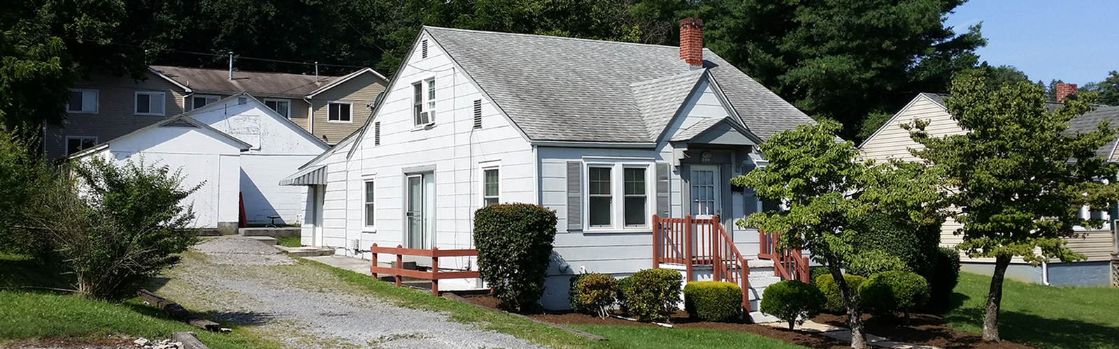 Charming cottage-style home with classic architecture, surrounded by lush greenery and vibrant landscaping.