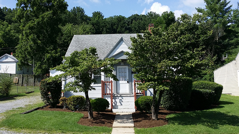 Charming cottage with lush landscaping and inviting front porch in a serene neighborhood.
