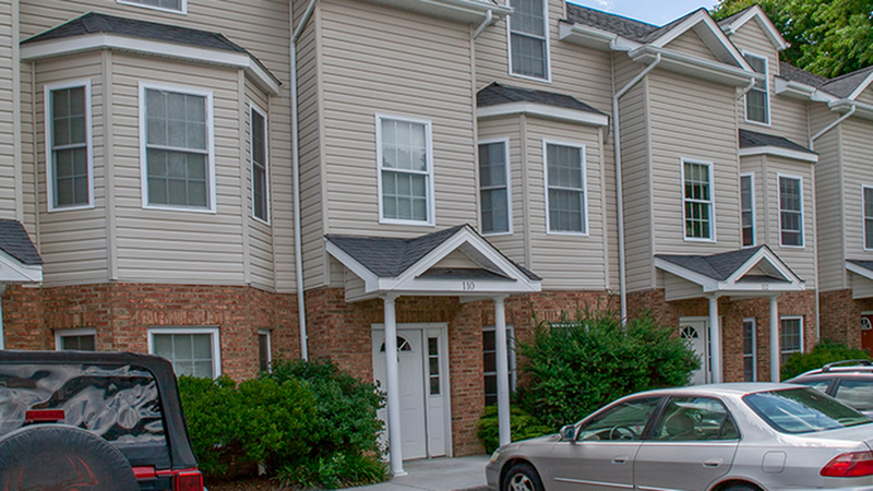 Charming townhouse exterior with elegant bay windows and inviting entryway, nestled in a lush suburban setting.