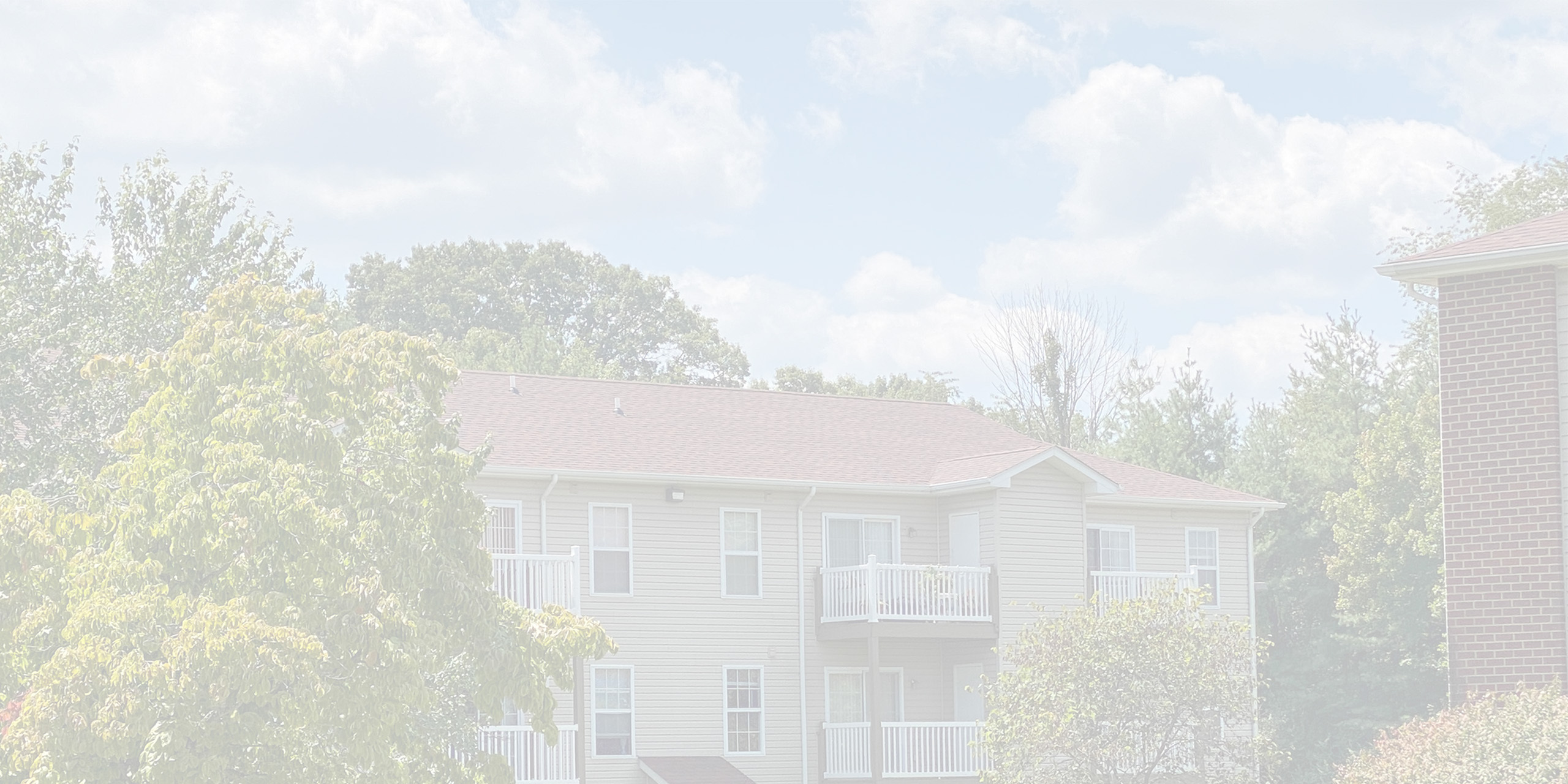 Charming suburban apartment with private balconies, surrounded by lush trees and greenery.