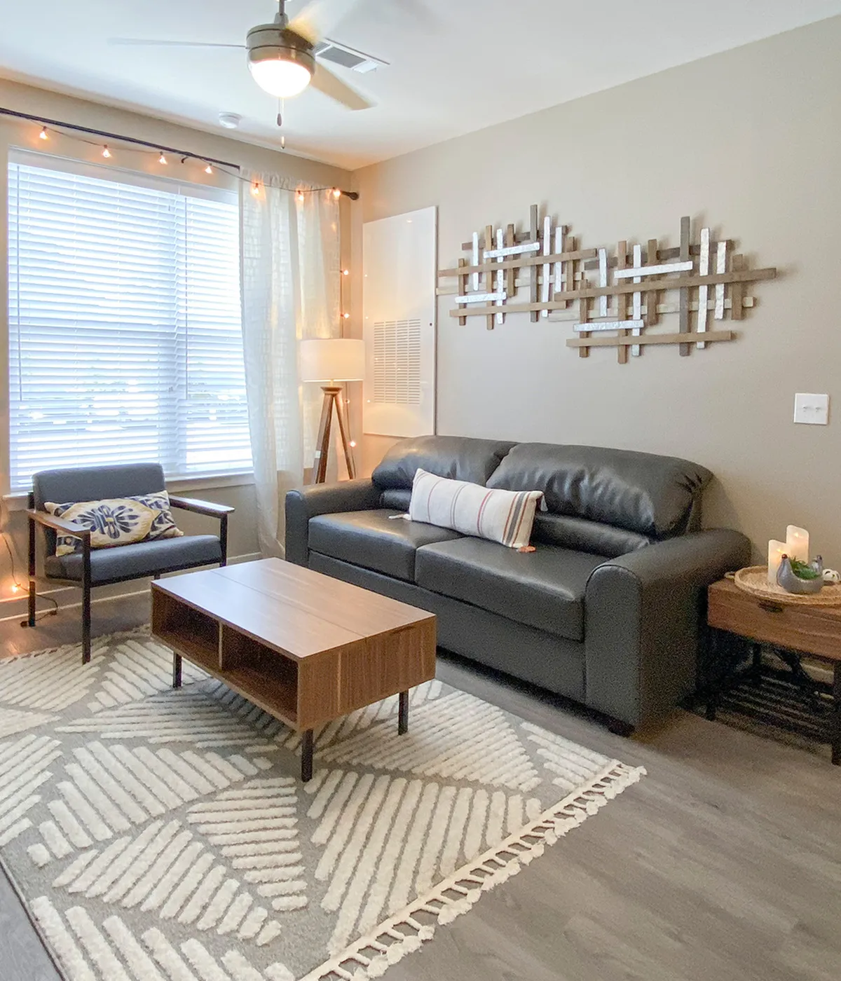 Chic living room with modern decor, featuring a comfortable black leather sofa, stylish armchair, and elegant wooden coffee table, illuminated by natural light through large windows.
