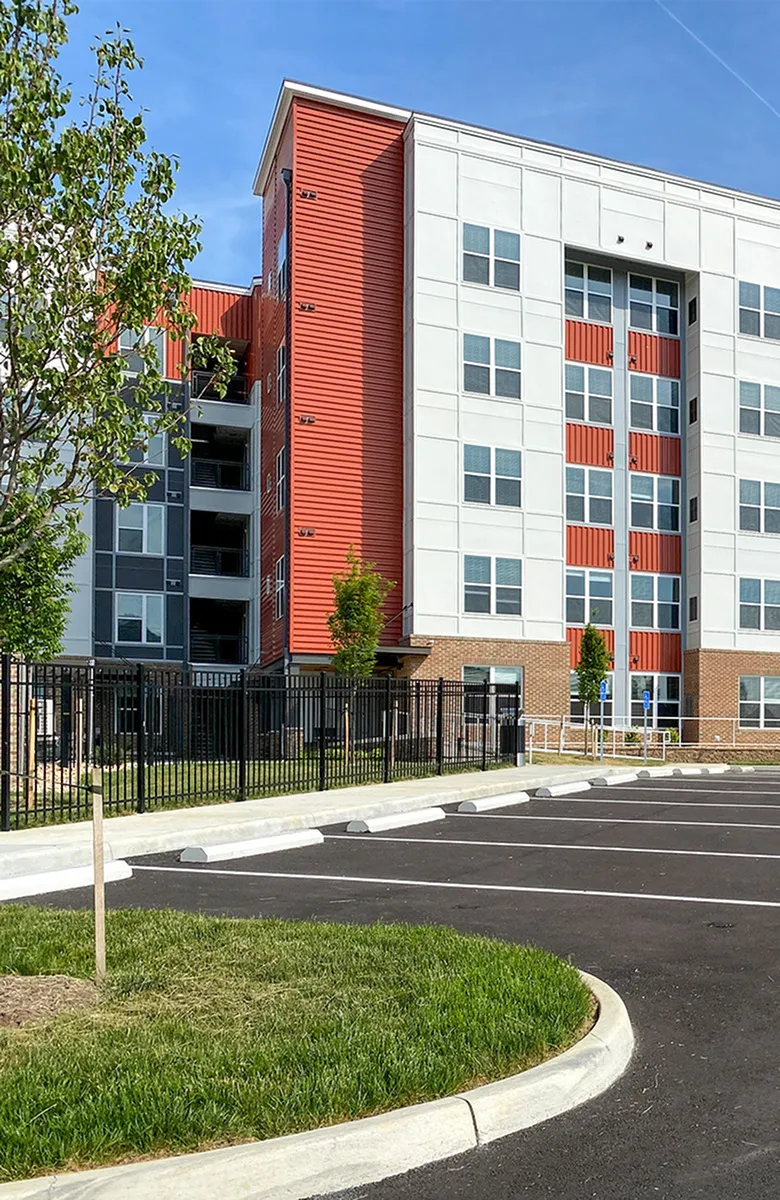 Contemporary apartment building showcasing modern architecture with vibrant red accents, ample windows, and a well-maintained exterior.