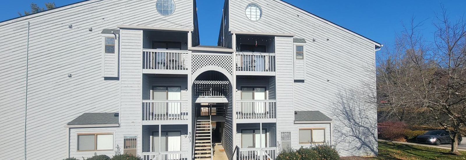 Charming apartment building with wooden architecture, featuring multiple balconies and a bright exterior on a clear day.
