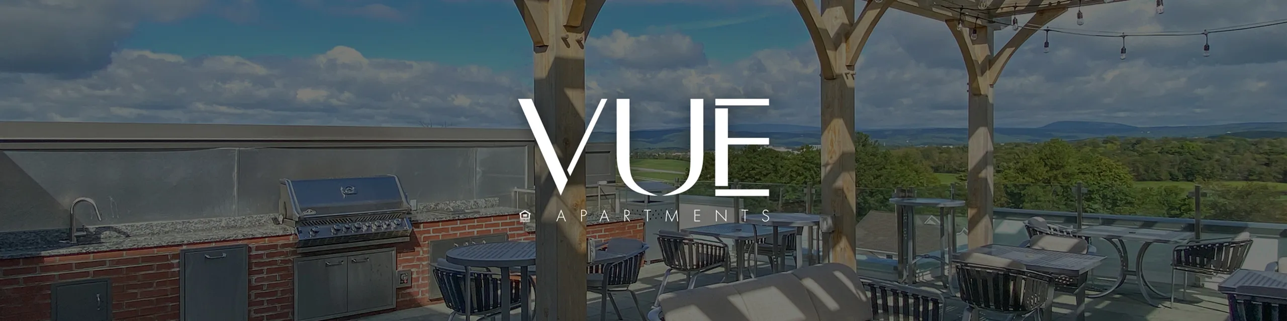 Charming rooftop terrace with modern grill, stylish seating, and scenic views at Vue Apartments.