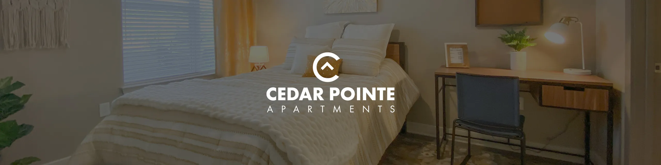 Inviting bedroom with cozy bedding, warm lighting, and a stylish workspace at Cedar Pointe Apartments.