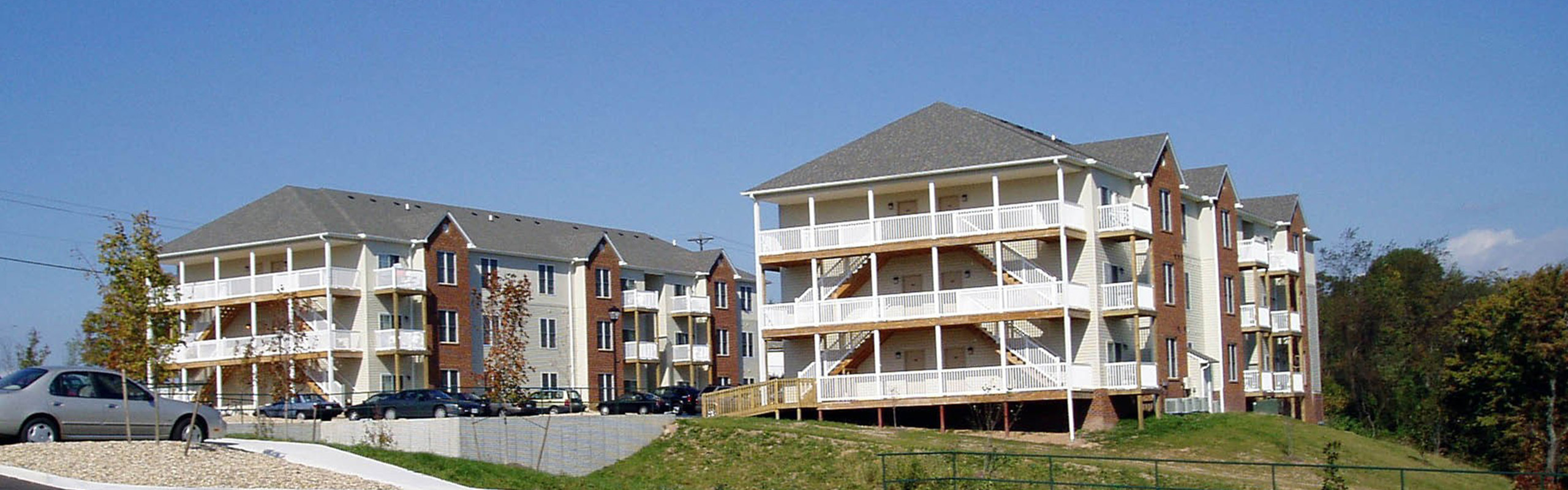 Charming apartment complex with spacious balconies and beautiful brick accents, nestled in a serene setting with lush greenery.