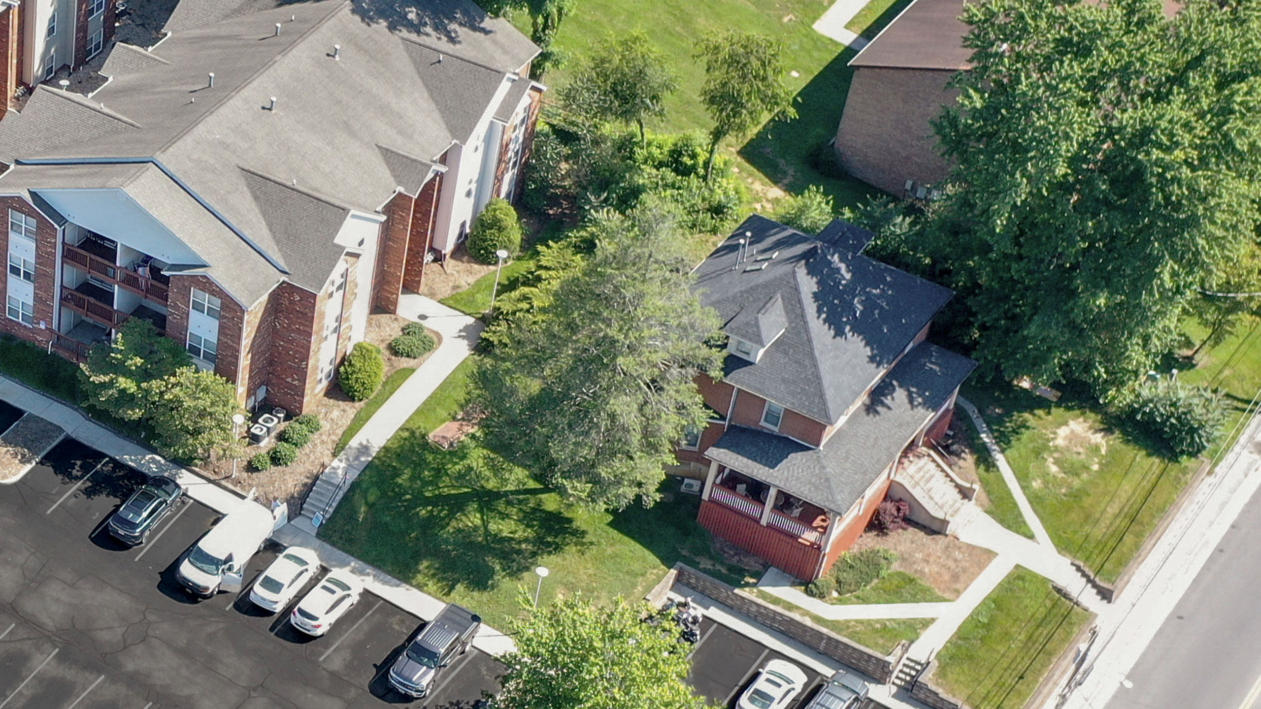 Aerial view of charming apartments surrounded by lush greenery, featuring convenient parking and a welcoming neighborhood atmosphere.