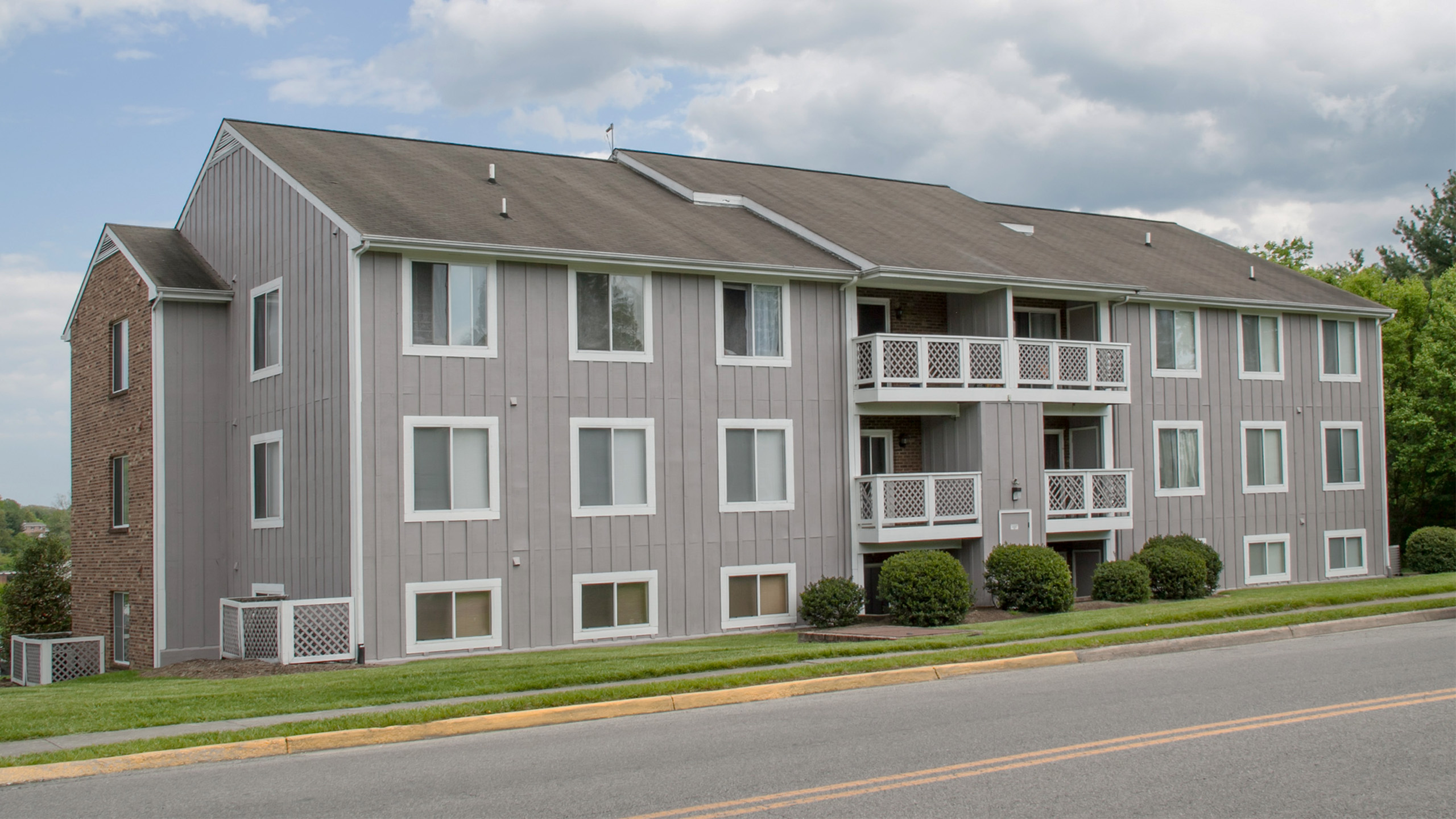 Charming apartment complex with a modern design, featuring spacious balconies and surrounded by lush greenery, perfect for serene living.