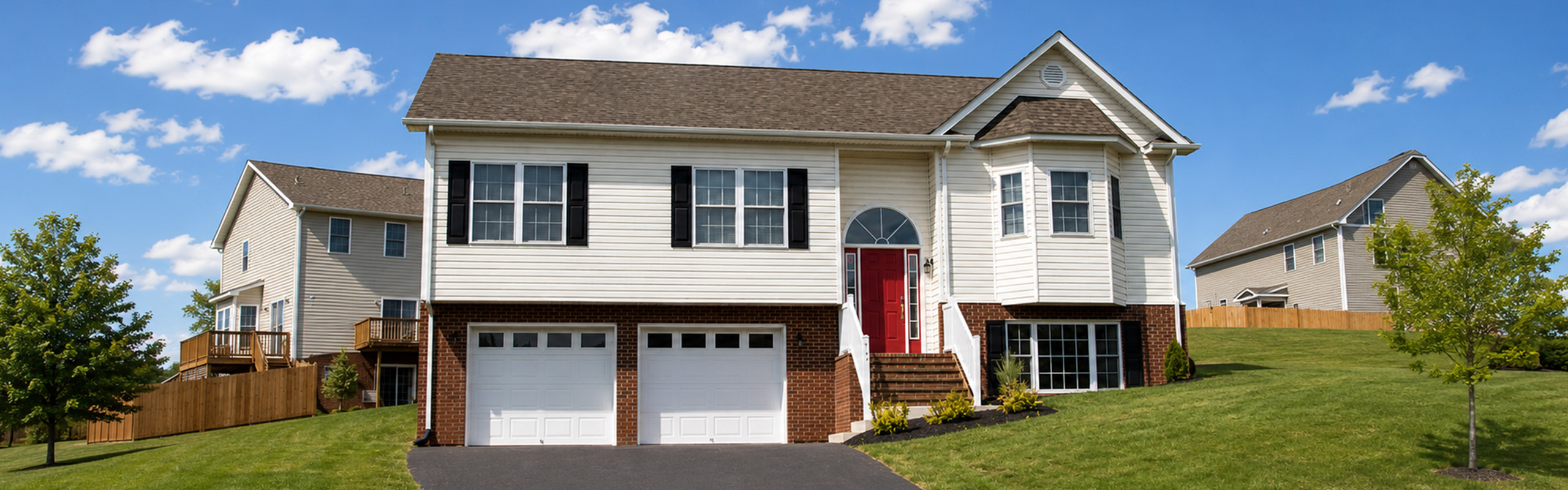 Charming two-story suburban home with a red door, double garage, and lush green lawn under a bright blue sky.