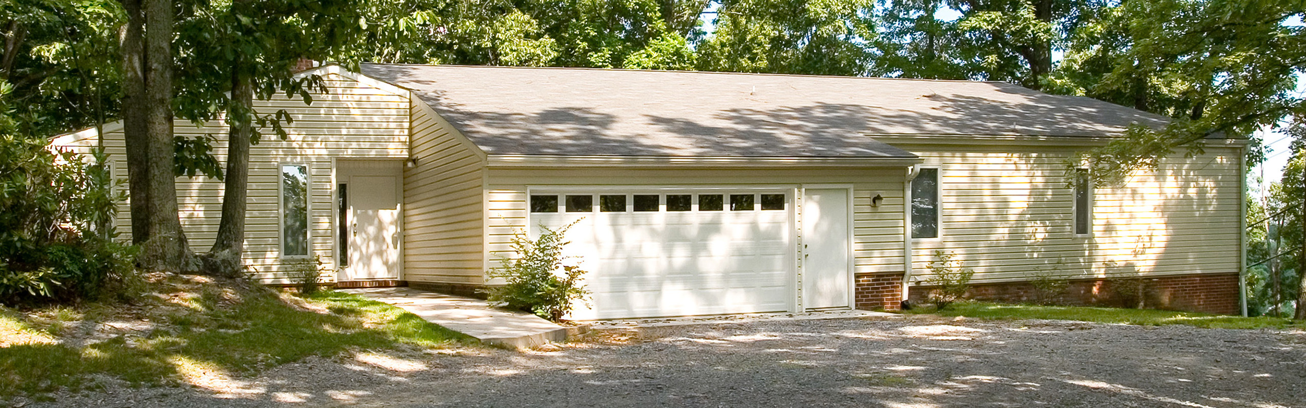 Charming single-story home with attached garage, nestled among lush greenery, offering serene living in a natural setting.