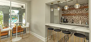 Elegant kitchen with modern bar stools, stylish pendant lights, and a vibrant tile backsplash overlooking a luxurious pool area.