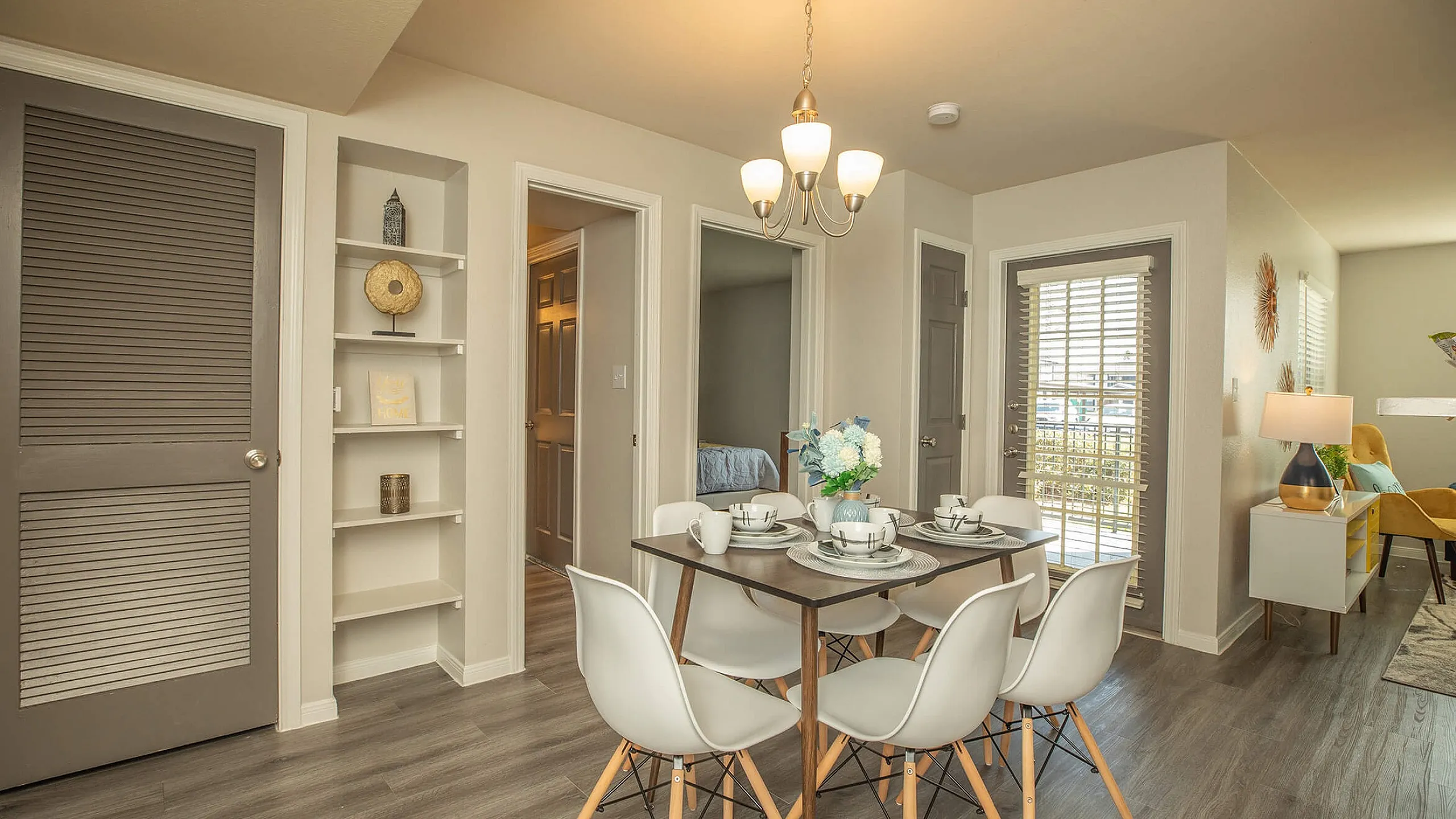 Modern dining area with elegant lighting, sleek wooden floors, and contemporary decor in a sunlit apartment.