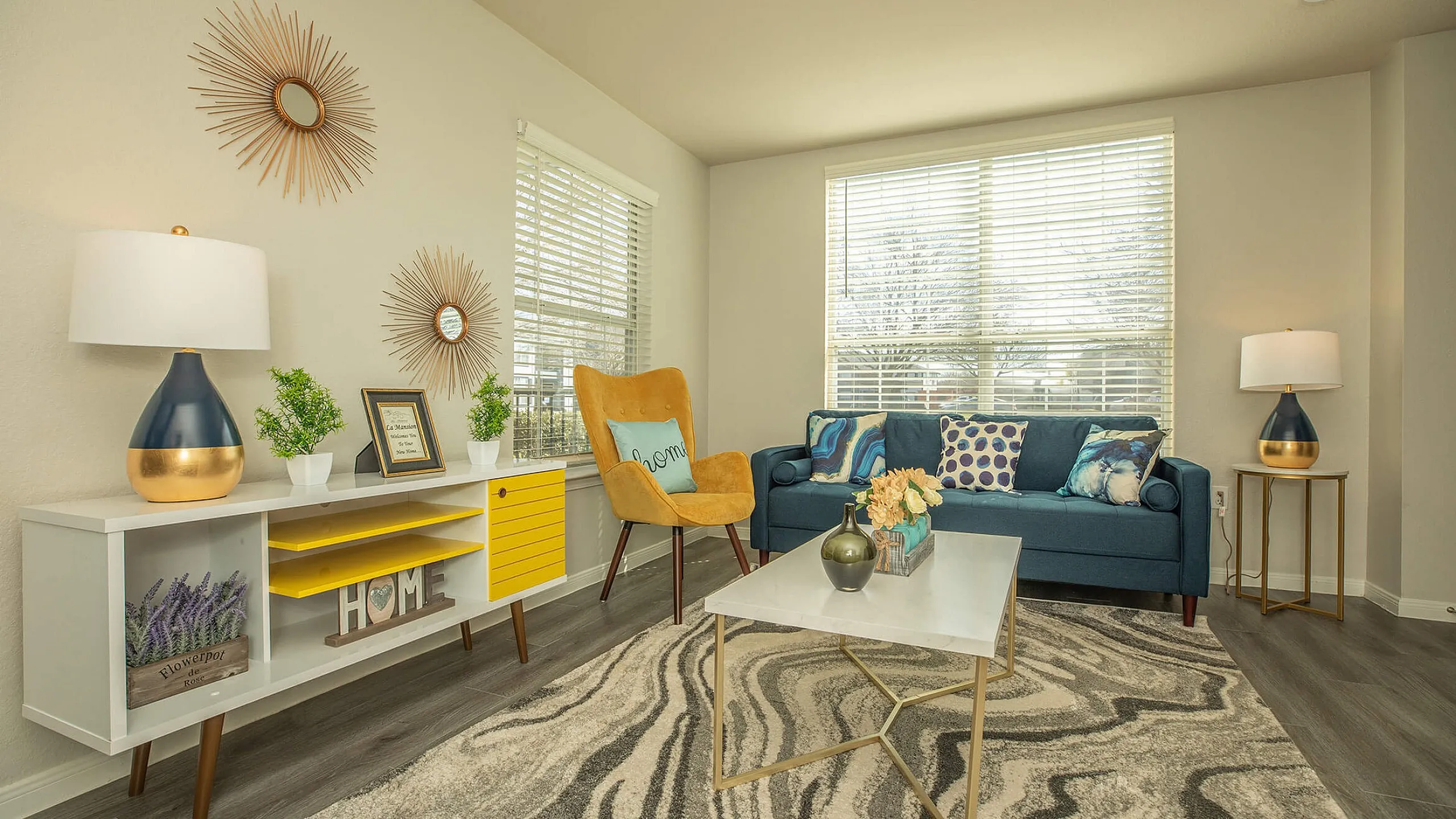 Chic living room with modern decor, featuring a plush blue sofa, stylish yellow armchair, and elegant coffee table under soft natural light.