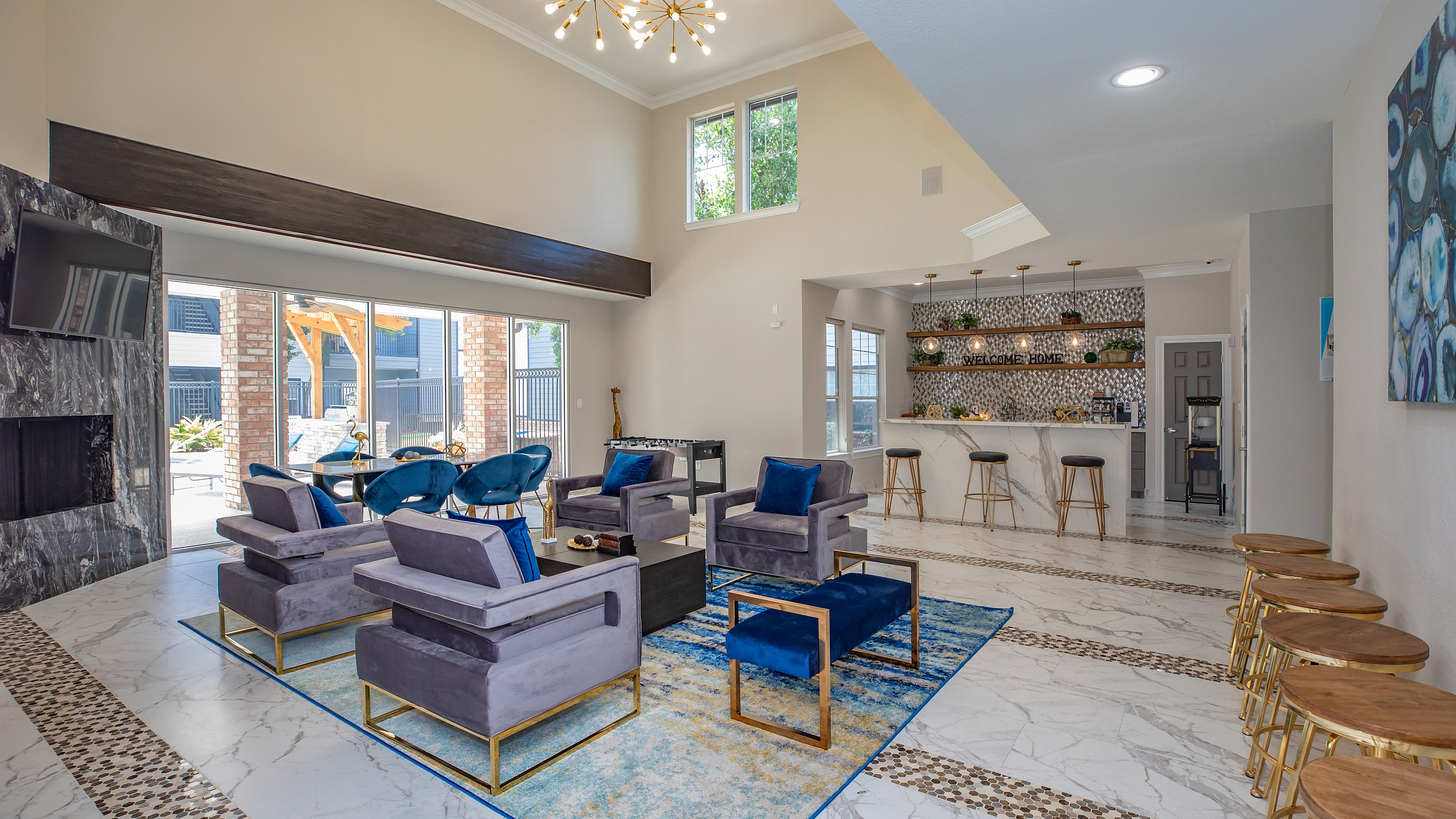 Elegant living space with high ceilings, modern chandelier, plush seating, and stylish bar area.