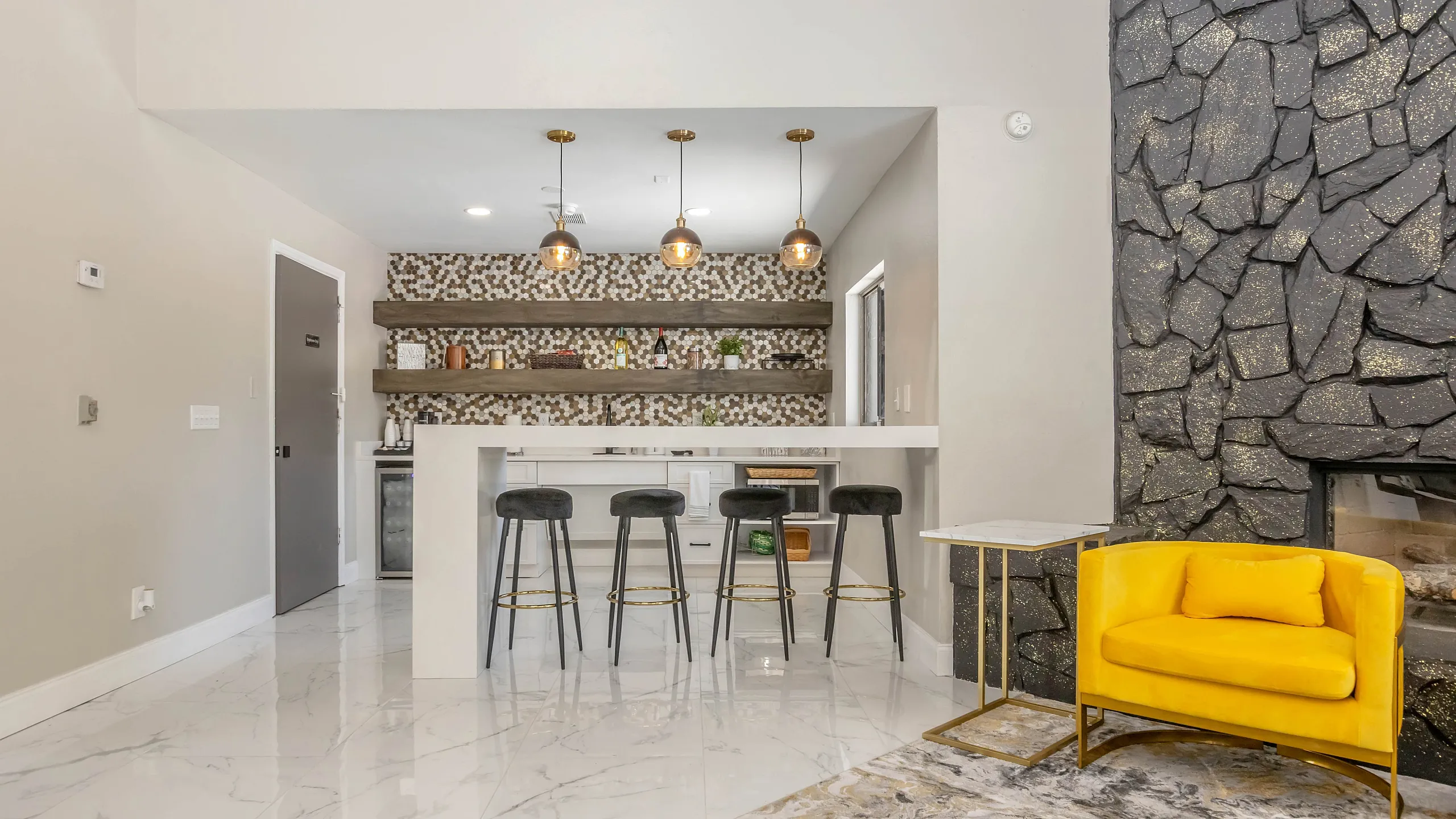 Contemporary living space showcasing a stylish breakfast bar with elegant lighting, cozy seating, and a striking stone accent wall.