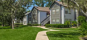 Charming apartments with classic architecture nestled in lush greenery, featuring scenic pathways and mature trees.