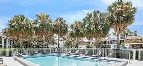 Inviting outdoor pool area surrounded by swaying palm trees and cozy lounge chairs, perfect for relaxation on a sunny day.