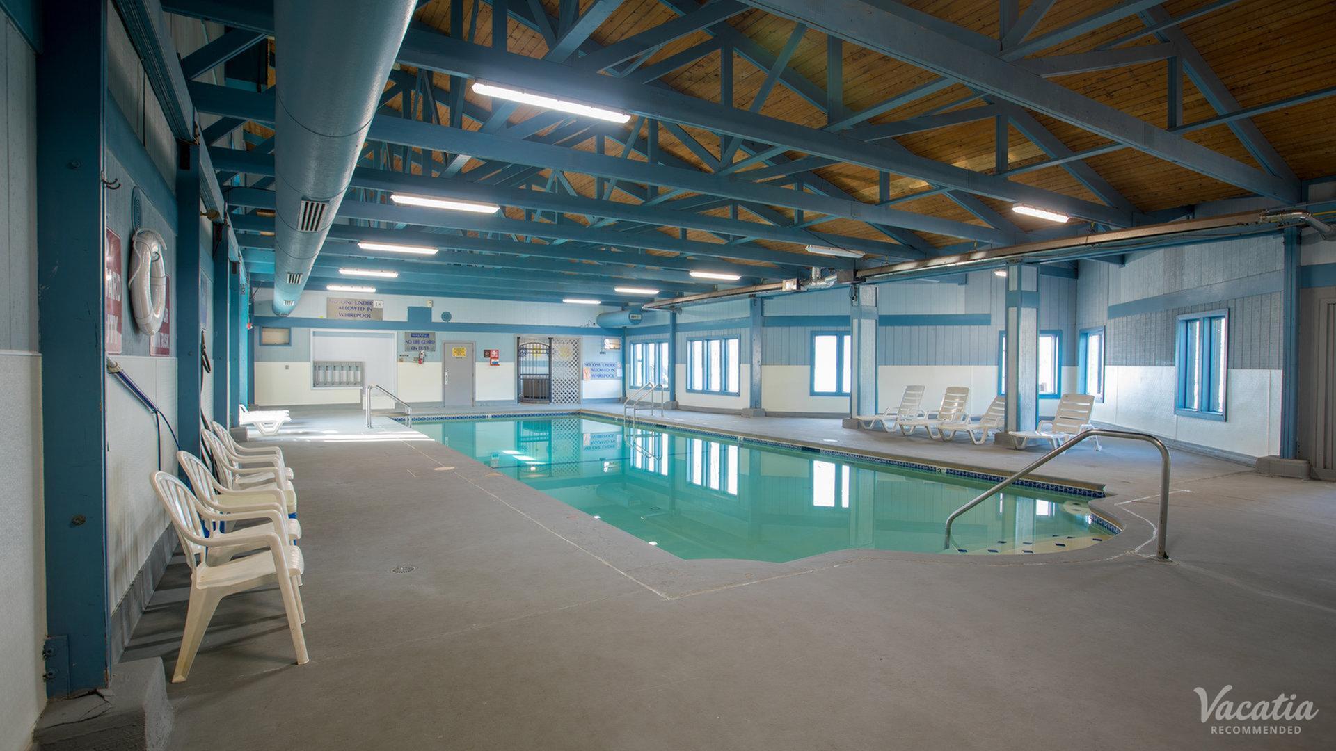 Spacious indoor pool with elegant seating, surrounded by modern architecture and ample lighting for a relaxing retreat.