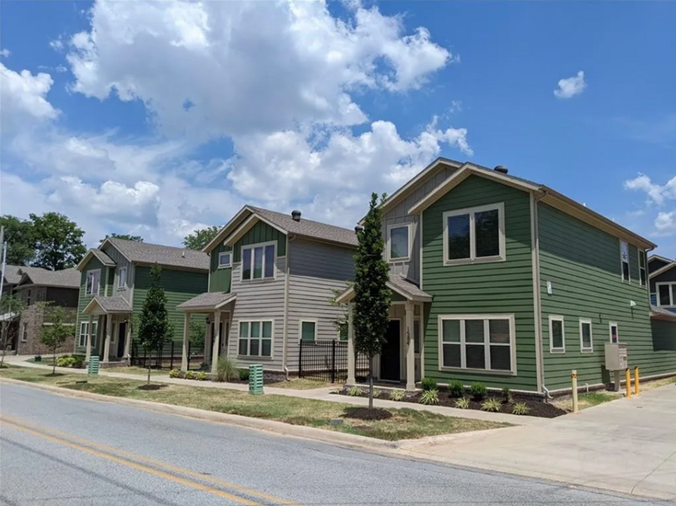 Charming suburban houses with modern designs and spacious layouts, nestled in a serene neighborhood under a bright blue sky.