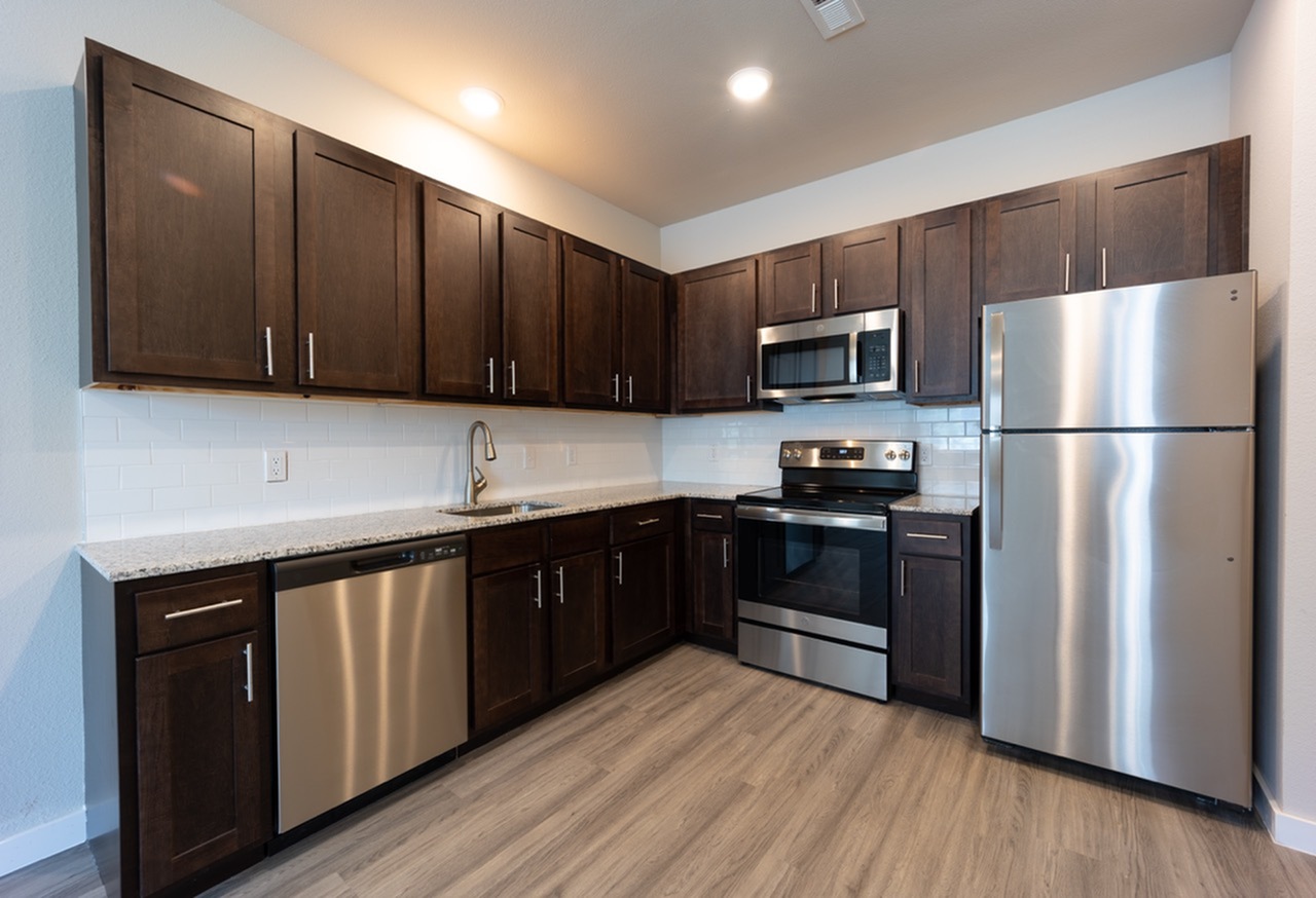 Modern kitchen with sleek stainless steel appliances, elegant dark wood cabinetry, and polished granite countertops.