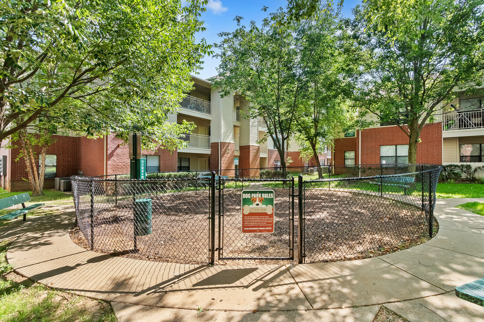 Charming apartment complex surrounded by lush greenery, featuring a welcoming dog park for pet-friendly living.