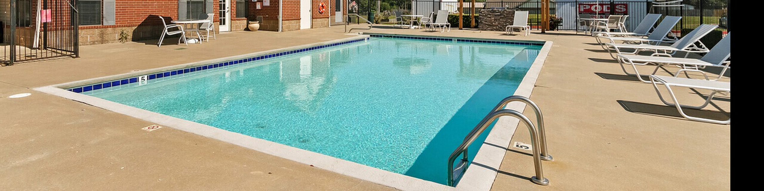 Inviting outdoor pool area with sleek lounge chairs and umbrellas, perfect for relaxation under the clear blue sky.