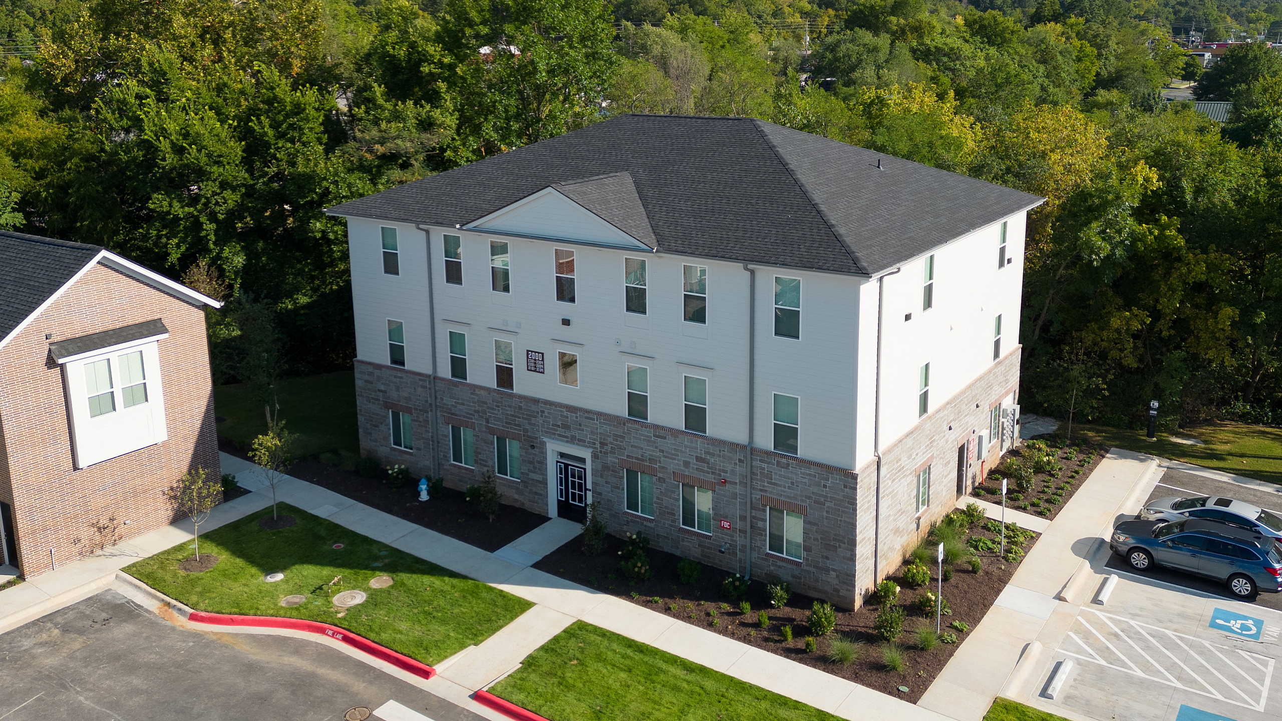 Charming three-story apartment building surrounded by lush greenery, ample parking, and modern designs in a peaceful setting.