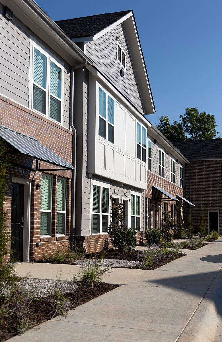 Charming modern townhouse with elegant brick and siding facade, featuring large windows and inviting entryways, perfect for comfortable urban living.