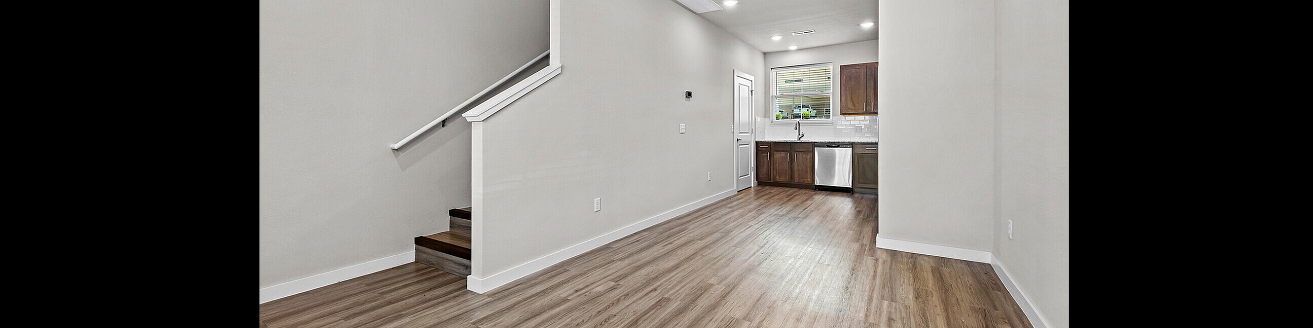 Modern open-concept living area with sleek kitchen, featuring stainless steel appliances and elegant wood flooring.