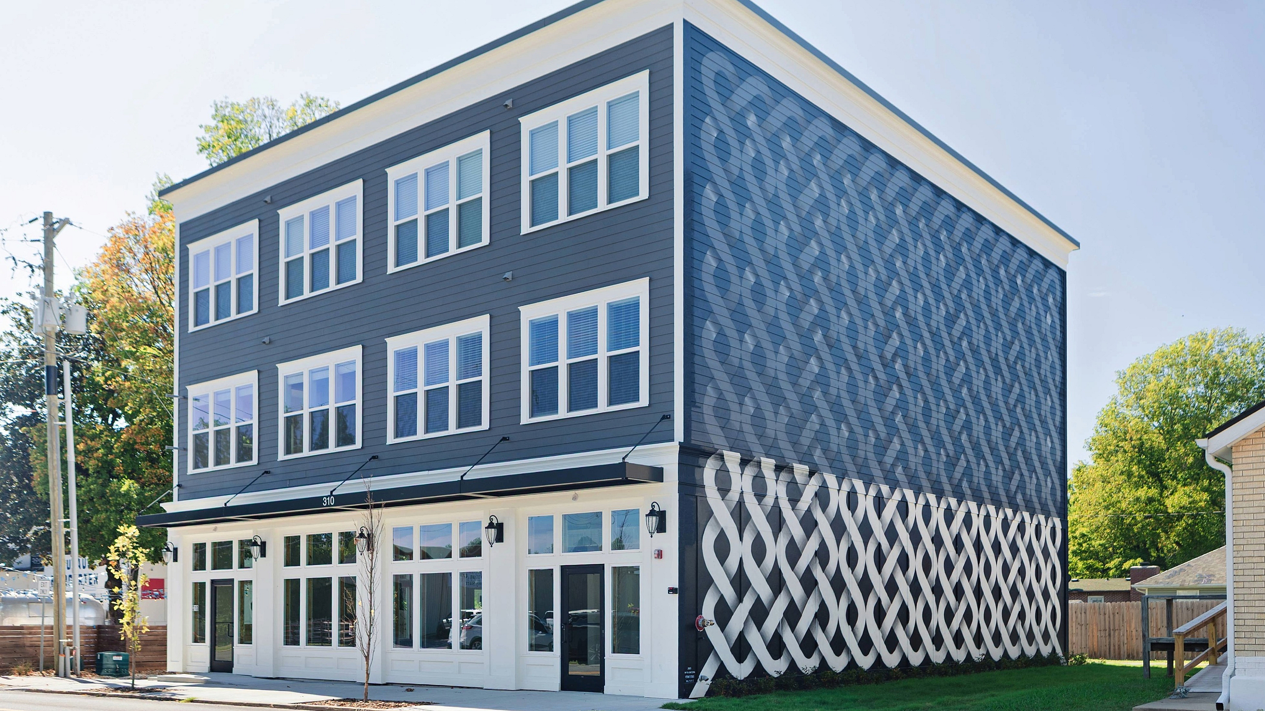 Modern three-story building with unique patterned facade and large windows, offering stylish urban living.