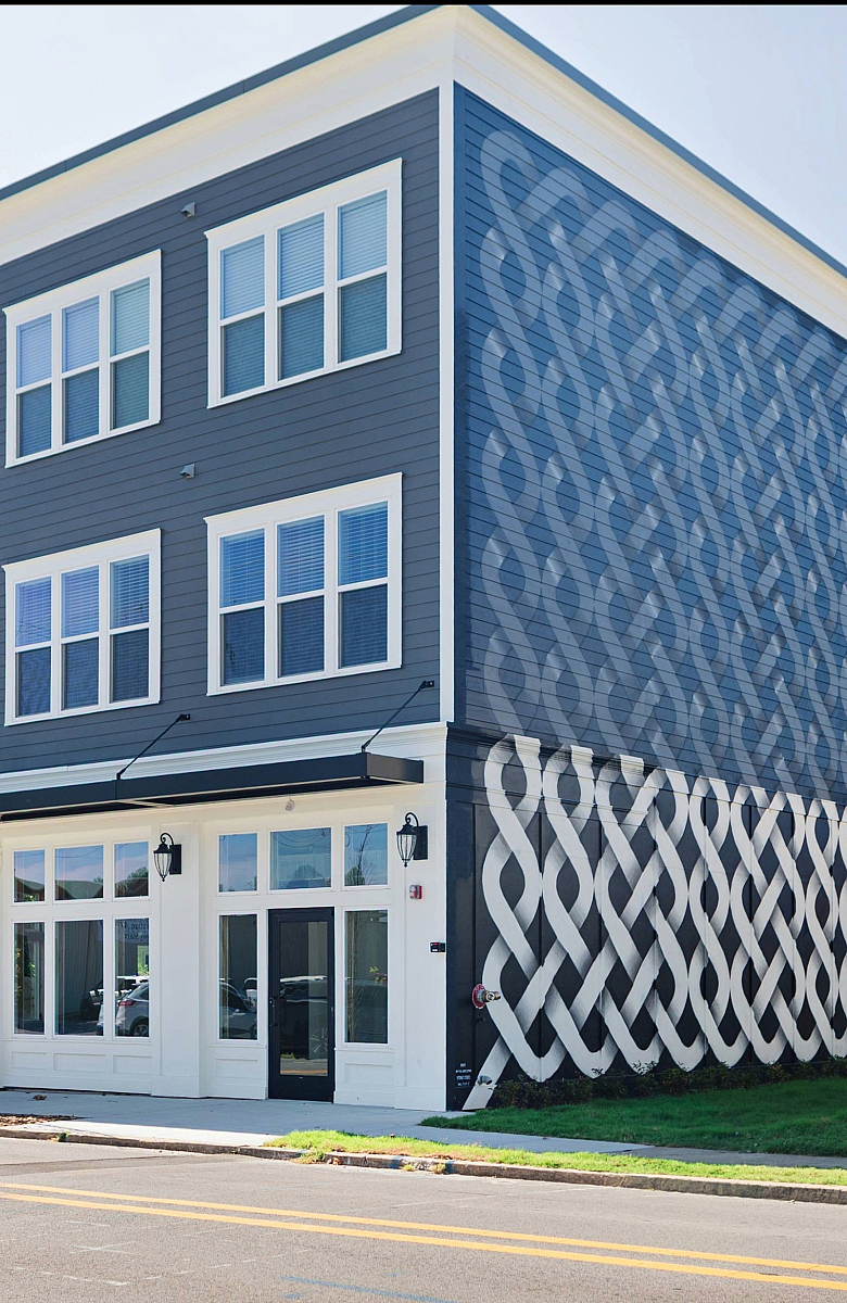 Modern three-story building with elegant blue and white facade, large windows, and contemporary architectural design.