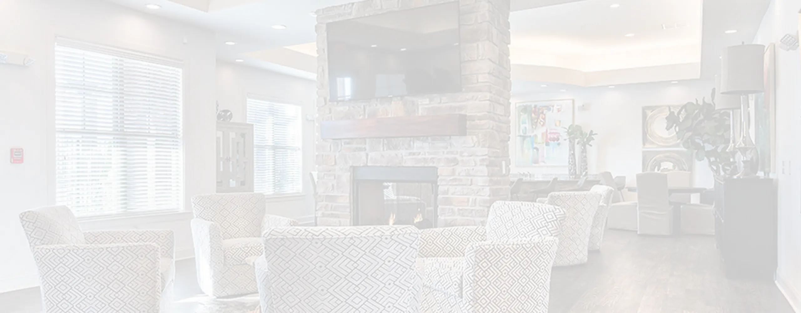 Bright and inviting living room with elegant armchairs, modern stone fireplace, and stylish decor, perfect for relaxation and entertainment.