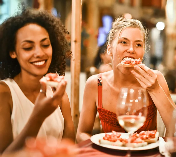Joyful evening with friends enjoying delicious Italian cuisine in a cozy, warmly lit restaurant, with wine and laughter.