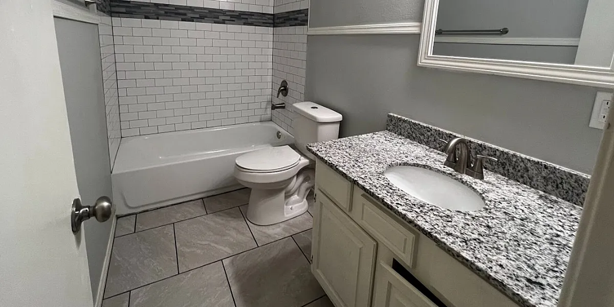 Contemporary bathroom with elegant white subway tiles, modern fixtures, and a sleek granite-topped vanity.