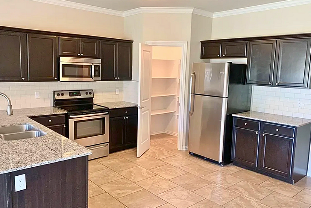 Modern kitchen with sleek dark cabinets, stainless steel appliances, and granite countertops, featuring a stylish island and spacious pantry.