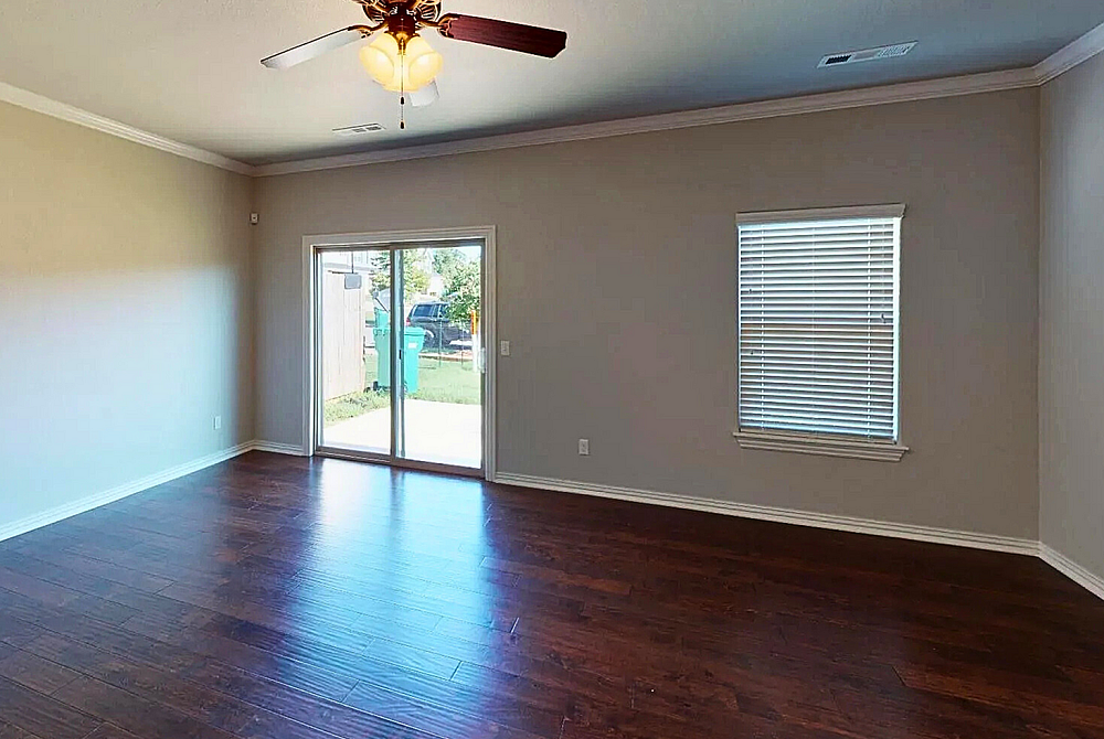 Inviting living room with elegant hardwood floors and abundant natural light through a sliding glass door.