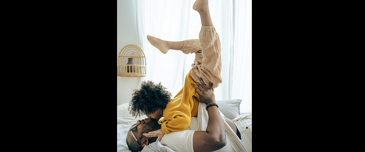 Bright, cozy bedroom with soft lighting, highlighting playful family moments, warmth, and comfort.