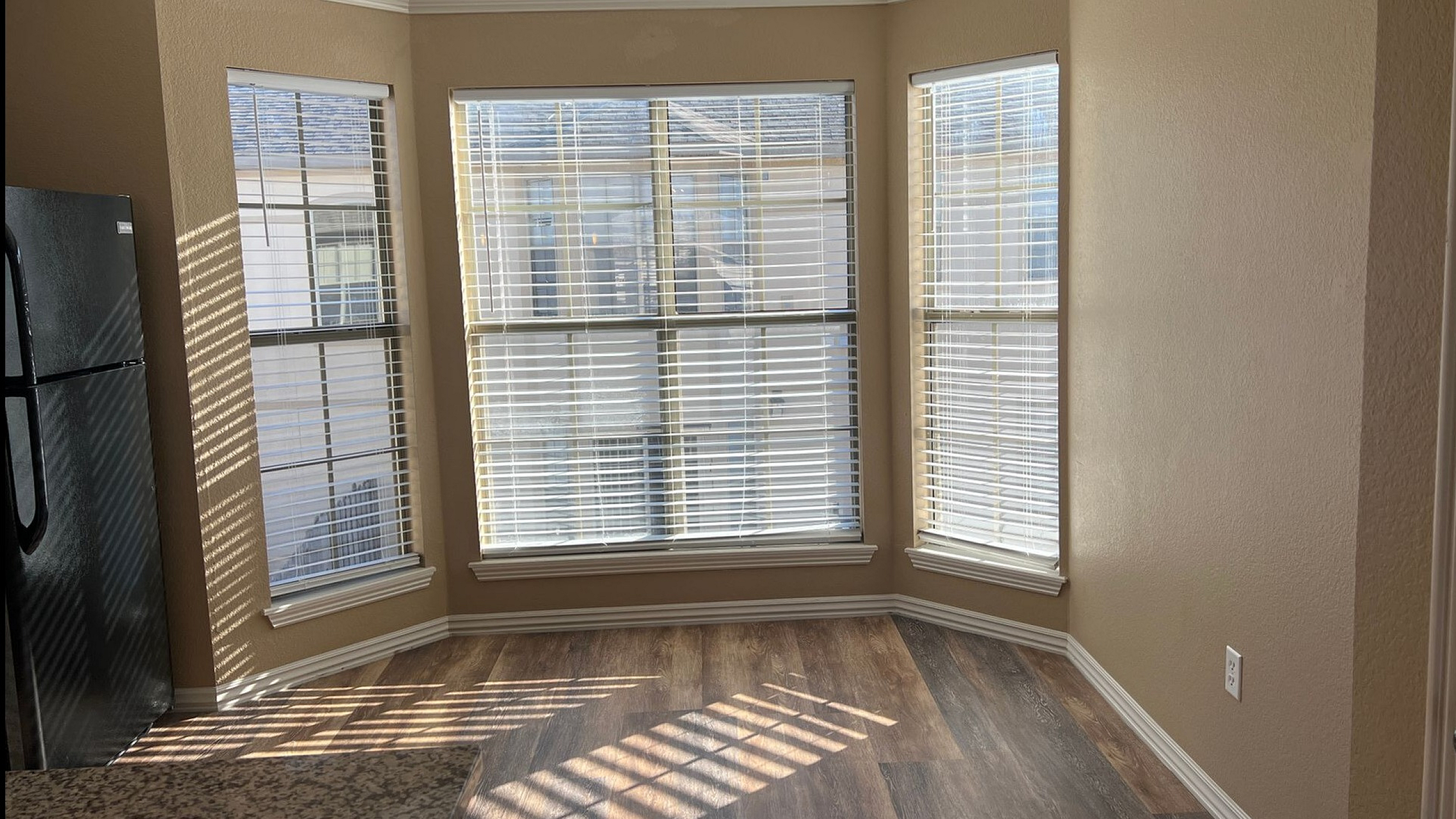 Bright and inviting kitchen nook with elegant crown molding, sunlit windows, and sleek hardwood flooring, perfect for morning coffee moments.