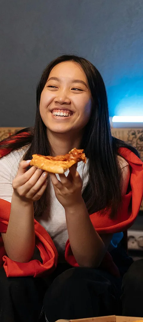 Lively gathering with friends enjoying pizza in a cozy, graffiti-adorned space with vibrant lighting.