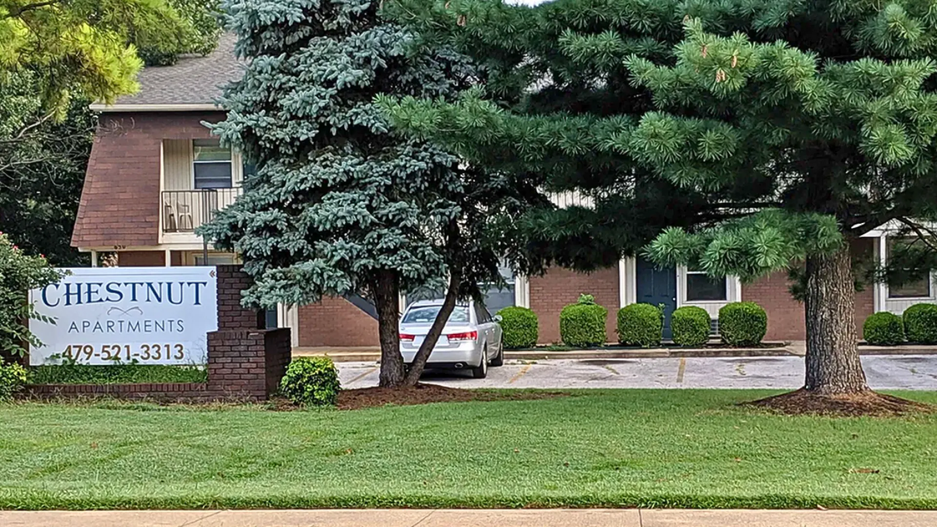 Inviting view of Chestnut Apartments with lush greenery and a welcoming atmosphere, highlighting accessible residential options and spacious parking.